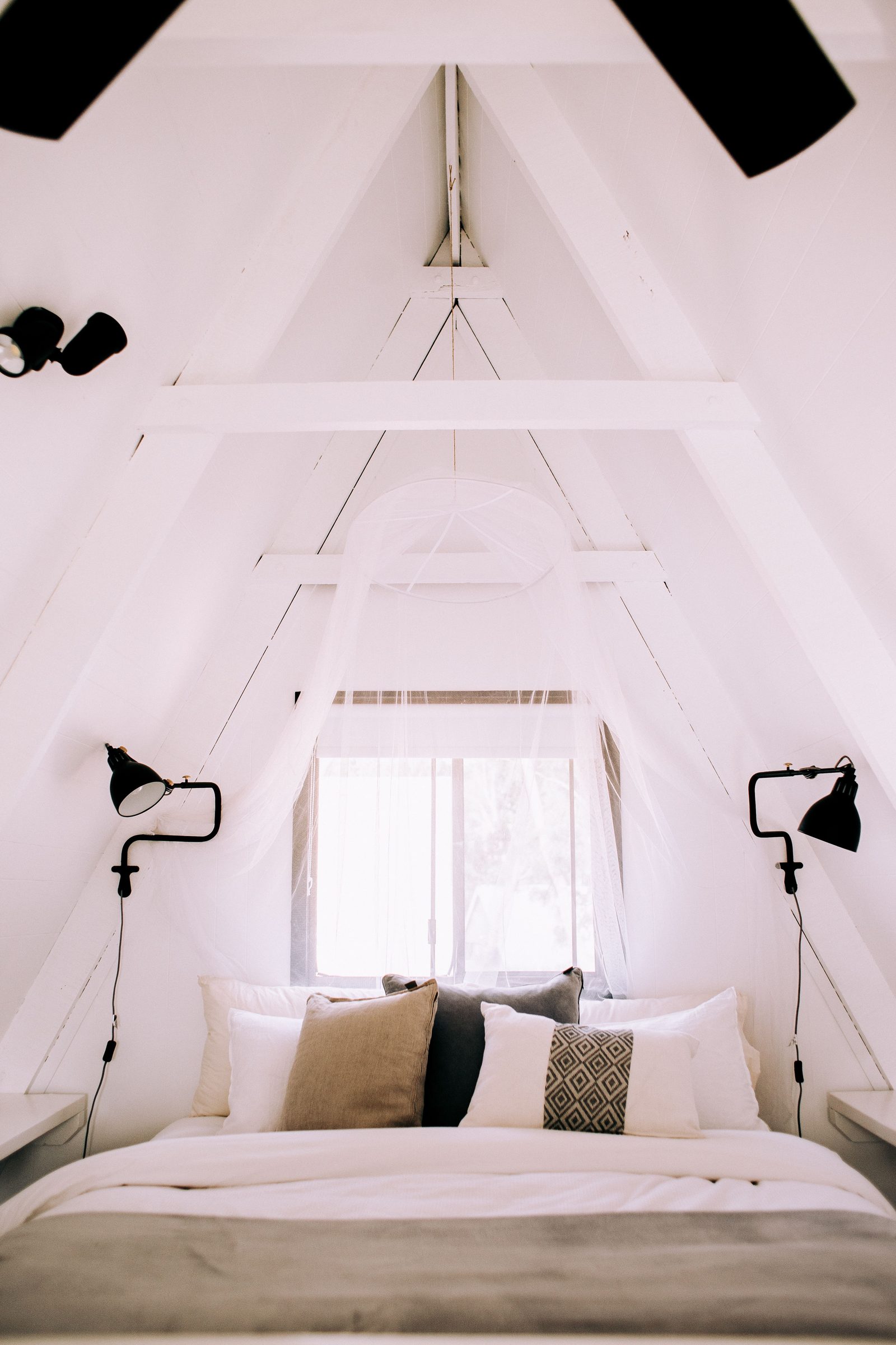 White A-frame attic bedroom with full-height ceiling after a mansard conversion