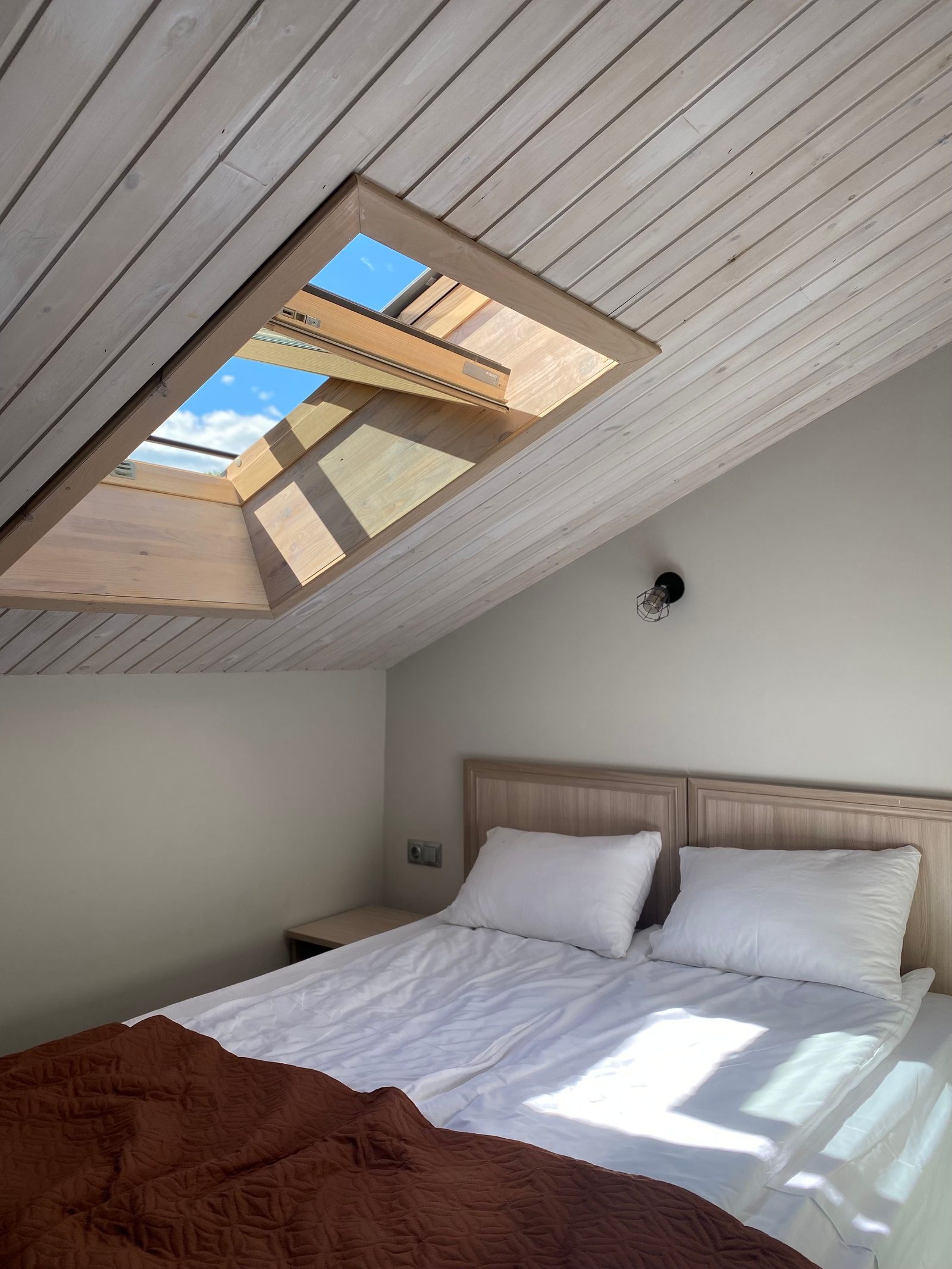 Double bed beneath an open roof window in a Velux loft conversion